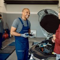 happy-african-american-auto-repairman-talking-customer-workshop-scaled.jpg